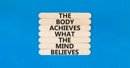 Mind and body symbol. Concept words The body achieves what the mind believes on wooden stick. Beautiful blue table blue background. Copy space. Motivational mind and body concept.の写真素材
