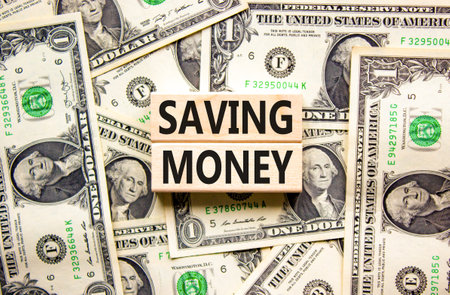 Saving money symbol. Concept words Saving money on wooden blocks on a beautiful background from dollar bills. Business, support and saving money concept. copyspace.の写真素材