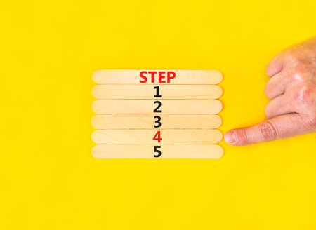 Time to step 4 symbol. Concept word Step 1 2 3 4 5 on wooden sticks. businessman hand. Beautiful yellow table yellow background. Business planning and time to step 4 concept. copyspace.の写真素材