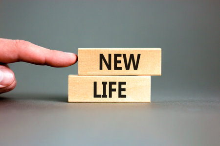 New life symbol. Concept words New life on wooden blocks on a beautiful gray table gray background. businessman hand. Business, support, motivation, psychological and new life concept. copyspace.の写真素材