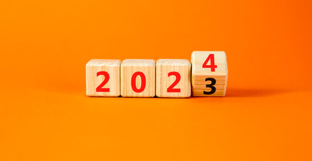 2024 happy new year symbol. Wooden cubes with number 2023 and 2024. Beautiful orange table orange background, copy space. Business and 2024 happy new year concept.の写真素材
