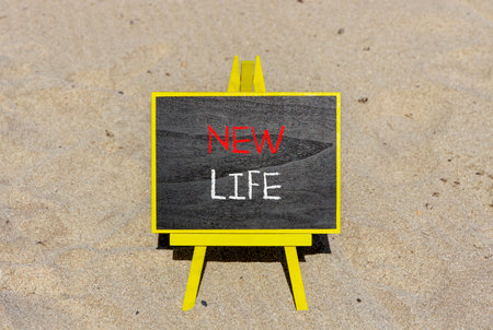 New life symbol. Concept words New life on wooden blocks on beautiful black blackboard on a beautiful beach sand background. Business, support, motivation psychological new life concept. copyspace.の写真素材