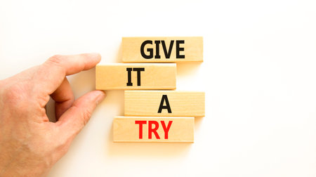 Give it a try symbol. Concept word Give it a try on beautiful wooden block. Beautiful white table white background. Businessman hand. Business give it a try concept. Copy space.の写真素材