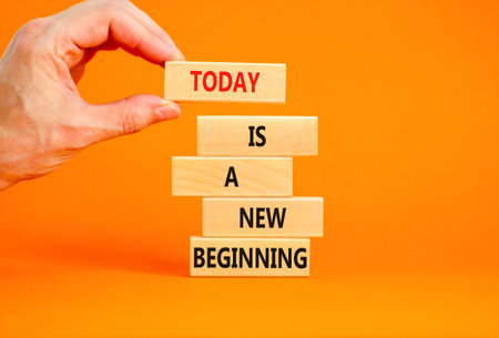 Today is a new beginning symbol. Concept words Today is a new beginning on wooden blocks. Beautiful orange background. Businessman hand. Business today is a new beginning concept. Copy space.の写真素材