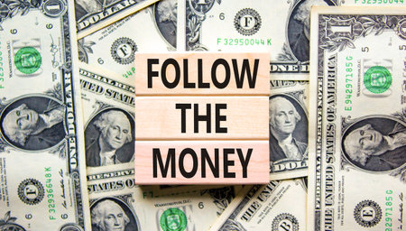 Follow the money symbol. Concept words Follow the money on beautiful wooden blocks. Dollar bills. Beautiful dollar bills background. Business and follow the money concept. Copy space.の写真素材