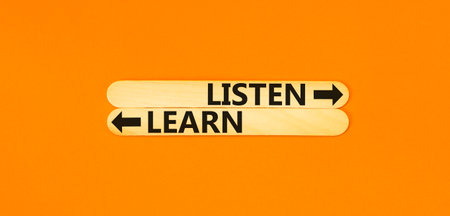Listen and learn symbol. Concept Listen and Learn on beautiful wooden stick. Beautiful orange table orange background. Business and listen and learn concept. Copy space.の写真素材