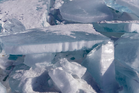 Winter natural background with fragments of blue ice and heaps of pieces of ice floes on Lake Baikal...