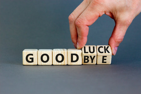Good luck or goodbye symbol. Concept words Good luck or Goodbye on beautiful wooden blocks. Beautiful gray background. Businessman hand. Business, motivational good luck concept. Copy space.の写真素材