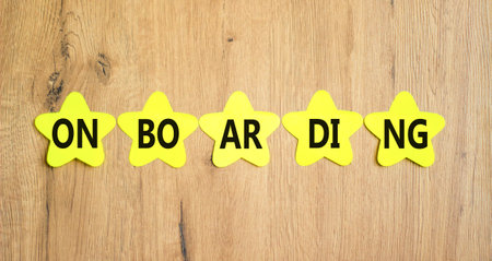 Onboarding success symbol. Concept word Onboarding on yellow paper stars. Beautiful wooden background. Business onboarding success concept. Copy space.の写真素材