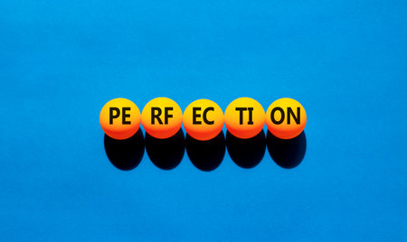 Perfection symbol. Concept word Perfection on beautiful yellow ping pong balls. Beautiful blue background. Business perfection concept. Copy space.の写真素材