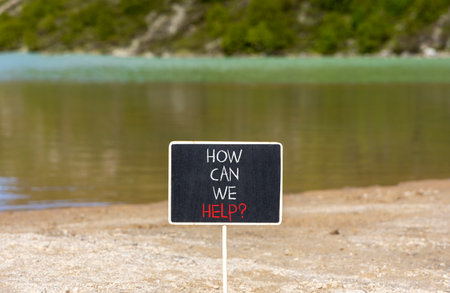 How can we help symbol. Concept words How can we help on beautiful black blackboard. Beautiful mountain lake background. Business and how can we help concept. Copy space.の写真素材