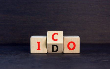 Initial coin or DEX offering symbol. Concept words abbreviation ICO or IDO on wooden block. Beautiful black table black background. Business Initial coin or DEX offering concept. Copy space.の写真素材