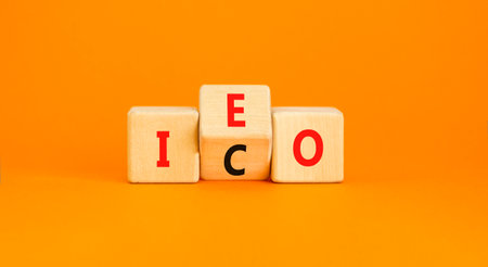 Initial coin or exchange offering symbol. Concept words abbreviation ICO or IEO on wooden block. Beautiful orange background. Business Initial coin or exchange offering concept. Copy space.の写真素材