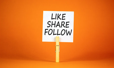 Like share follow symbol. Concept words Like Share Follow on beautiful white paper on clothespin. Beautiful orange background. Business like share follow concept. Copy space.の写真素材
