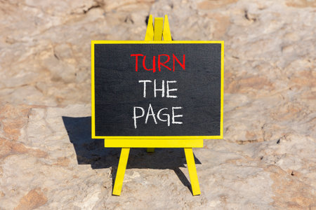 Turn the page symbol. Concept words Turn the page on beautiful blackboard. Beautiful brown stone beach background. Business motivational lifestyle turn the page concept. Copy space.の写真素材