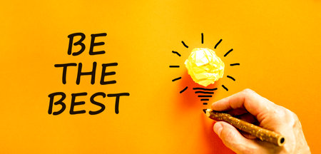 Motivational be the best symbol. Concept words Be the best on beautiful orange paper. Beautiful orange background. Businessman hand. Light bulb. Business motivational be the best concept. Copy space.の写真素材
