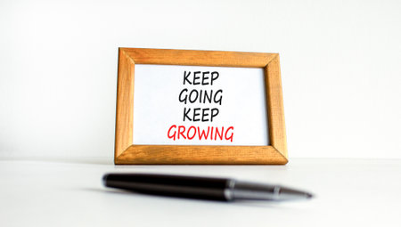 Keep going and growing symbol. Concept words phrase Keep going keep growing on beautiful wooden picture frame. Beautiful white background. Business Keep going and growing concept. Copy space.の写真素材