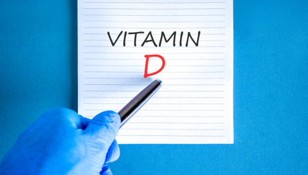Vitamin D symbol. Concept words Vitamin D on beautiful white note. Doctor's hand in blue medical glove. Black pen. Beautiful blue background. Medical healthy lifestyle Vitamin D concept.の写真素材