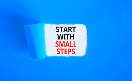 Start with small steps symbol. Concept words phrase Start with small steps on beautiful white paper. Beautiful blue paper background. Business Start with small steps concept. Copy space.の写真素材