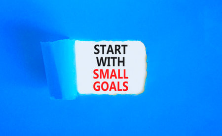 Start with small goals symbol. Concept words phrase Start with small goals on beautiful white paper. Beautiful blue paper background. Business Start with small goals concept. Copy space.の写真素材