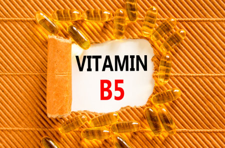 Vitamin B5 pantothenic acid symbol. Concept words Vitamin B5 on beautiful white paper. Yellow pills tablets. Beautiful brown background. Medical healthy lifestyle Vitamin B5 concept.の写真素材