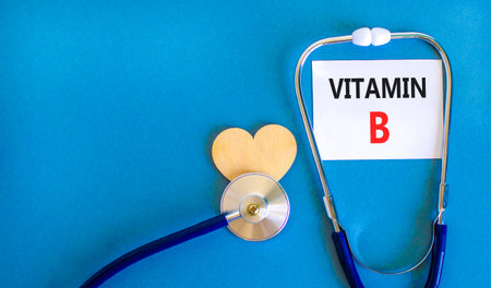 Vitamin B symbol. Concept words Vitamin B on beautiful white card. Wooden heart and stethoscope. Beautiful blue background. Medical healthy lifestyle Vitamin B concept.の写真素材