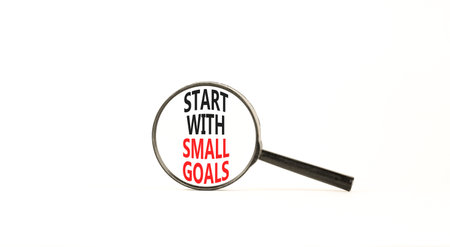 Start with small goals symbol. Concept words phrase Start with small goals in beautiful black magnifying glass. Beautiful white background. Business Start with small goals concept. Copy space.の写真素材