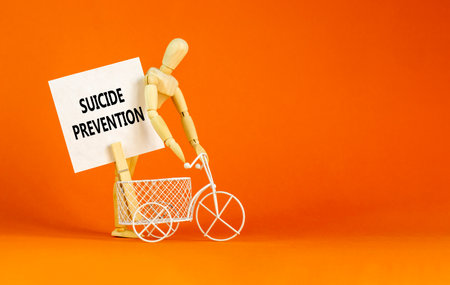 Suicide prevention symbol. Concept words Suicide prevention on beautiful white paper on clothespin. Beautiful orange table orange background. Psychological and suicide prevention concept. Copy space.の写真素材