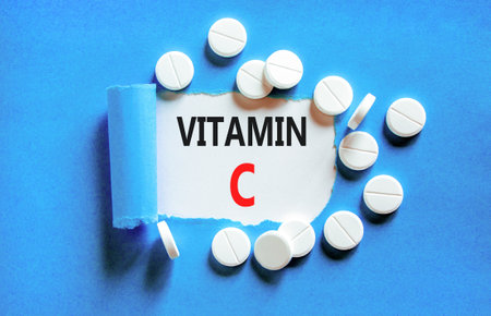 Vitamin C symbol. Concept words Vitamin C on beautiful white paper. White pills tablets. Beautiful blue background. Healthy lifestyle Vitamin C concept.の写真素材