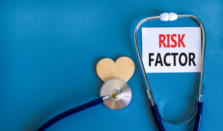 Risk factor symbol. Concept words Risk factor on beautiful white card. Wooden heart and stethoscope. Beautiful blue background. Medical healthy lifestyle risk factor concept.の写真素材
