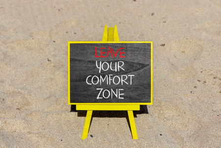 Leave your comfort zone symbol. Concept words Leave your comfort zone on beautiful black blackboard. Beautiful sand beach background. Business psychological Leave your comfort zone concept. Copy spaceの写真素材