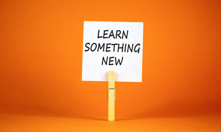 Learn something new symbol. Concept words Learn something new on beautiful white paper on clothespin. Beautiful orange background. Business motivational learn something new concept. Copy space.の写真素材