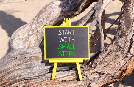 Start with small steps symbol. Concept words phrase Start with small steps on beautiful black blackboard. Beautiful old tree background. Business Start with small steps concept. Copy space.の写真素材