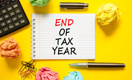 End of tax year symbol. Concept words phrase End of tax year on beautiful white note. Colored paper. Calculator. Beautiful yellow background. Business End of tax year concept. Copy space.の写真素材