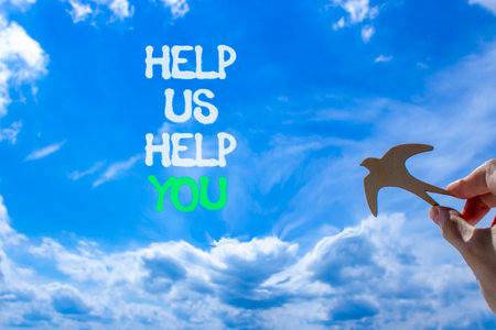 Help you symbol. Concept words phrase Help us help you on beautiful blue sky. Businessman's hand. Beautiful blue sky clouds background. Business Help you concept. Copy space.の写真素材