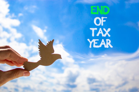 End of tax year symbol. Concept words phrase End of tax year on beautiful blue sky. Businessman's hand. Beautiful blue sky clouds background. Business End of tax year concept. Copy space.の写真素材