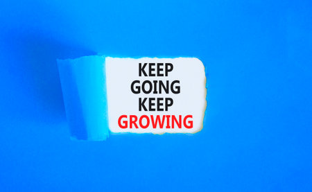 Keep going and growing symbol. Concept words phrase Keep going keep growing on beautiful white paper. Beautiful blue paper background. Business Keep going and growing concept. Copy space.の写真素材