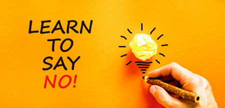 Learn to say no symbol. Concept words phrase Learn to say no on beautiful orange paper. Businessman's hand. Beautiful orange background. Business psychological Learn to say no concept. Copy space.の写真素材