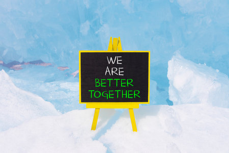 We are better together symbol. Concept words phrase We are better together on beautiful black blackboard. Beautiful blue ice background. Business We are better together concept. Copy space.の写真素材