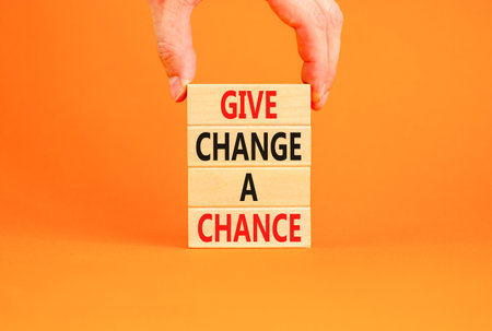 Give change a chance symbol. Concept words phrase Give change a chance on beautiful wooden blocks Beautiful orange paper background. Businessman's hand Business Give change a chance concept Copy spaceの写真素材