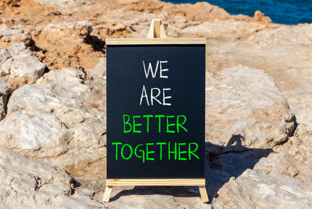 We are better together symbol. Concept words phrase We are better together on beautiful black blackboard. Beautiful stone blue sea sky background. Business We are better together concept. Copy space.の写真素材