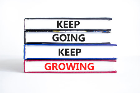 Keep going and growing symbol. Concept words phrase Keep going keep growing on beautiful books. Beautiful white paper background. Business Keep going and growing concept. Copy space.の写真素材