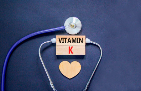 Vitamin K phylloquinone symbol. Concept words Vitamin K on beautiful wooden blocks. Wooden heart and stethoscope. Beautiful black background. Medical healthy lifestyle Vitamin K phylloquinone concept.の写真素材