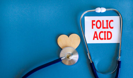 Folic acid symbol. Concept words Folic acid on beautiful white card. Wooden heart and stethoscope....