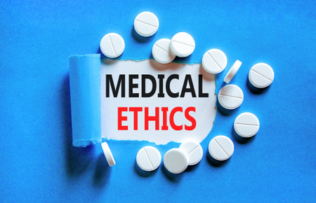 Medical ethics symbol. Concept words Medical ethics on beautiful white paper. White pills tablets. Beautiful blue background. Medical healthy lifestyle medical ethics concept.の写真素材
