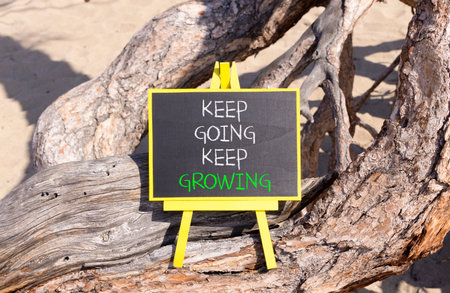 Keep going and growing symbol. Concept words phrase Keep going keep growing on beautiful black blackboard. Beautiful old tree background. Business Keep going and growing concept. Copy space.の写真素材