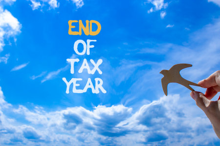 End of tax year symbol. Concept words phrase End of tax year on beautiful blue sky. Businessman's hand. Beautiful blue sky clouds background. Business End of tax year concept. Copy space.の写真素材