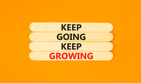 Keep going and growing symbol. Concept words phrase Keep going keep growing on beautiful wooden stick. Beautiful orange paper background. Business Keep going and growing concept. Copy space.の写真素材