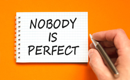 Nobody is perfect symbol. Concept words Nobody is perfect on beautiful white note. Beautiful orange background. Businessman hand. Business motivational lifestyle nobody is perfect concept. Copy space.の写真素材