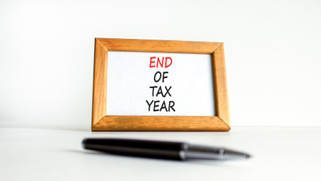 End of tax year symbol. Concept words phrase End of tax year on beautiful wooden picture frame. Black pen. Beautiful white background. Business End of tax year concept. Copy space.の写真素材
